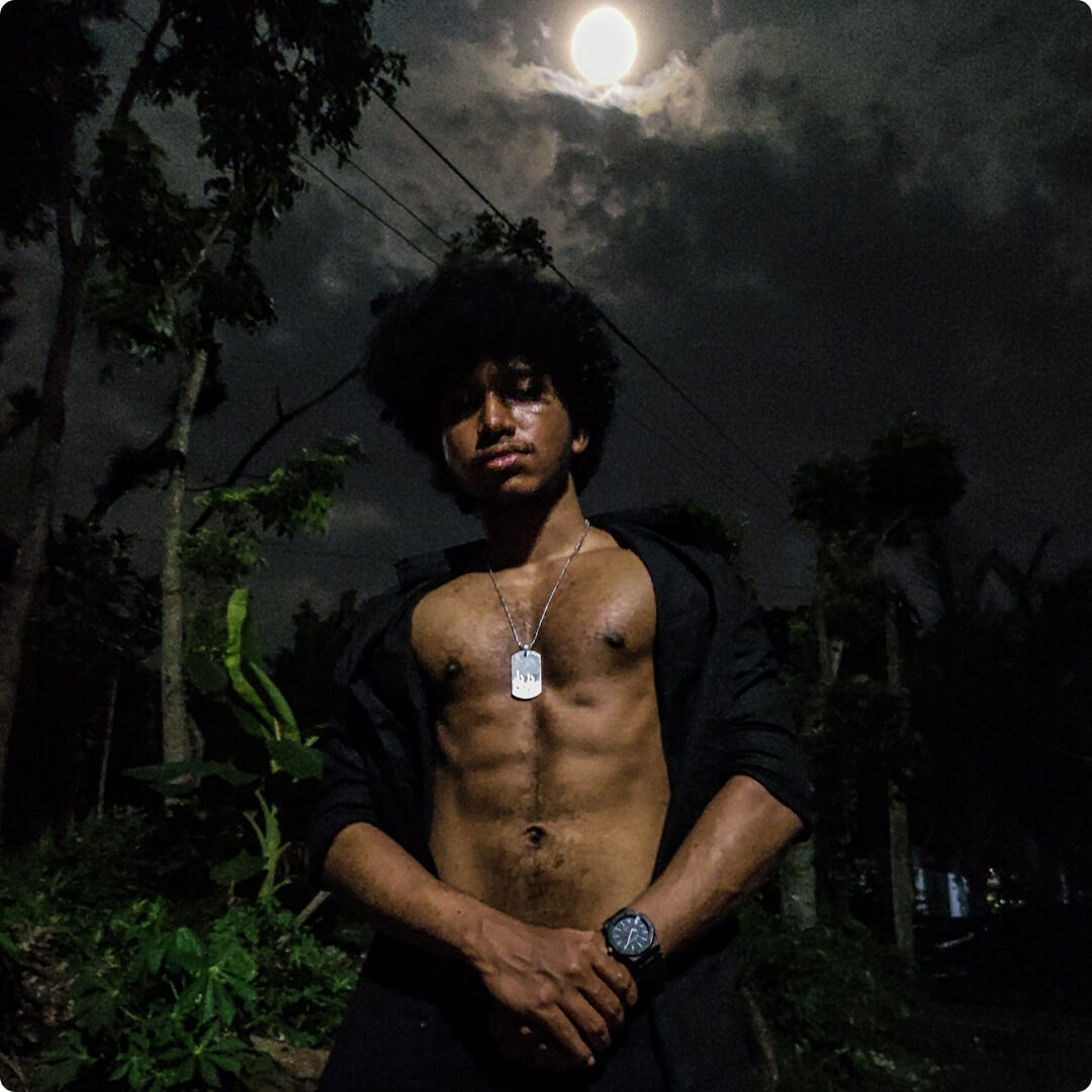 a shirtless bodybuildr in a black shirt wearing a dog tag standing in front of a full moon with a wrist watch on his hand Mobile