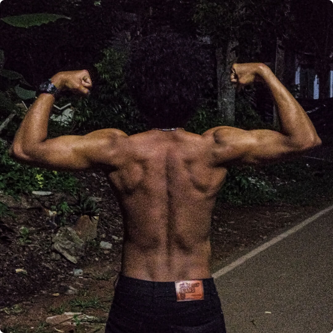 the back of a bodybuilder flexing his muscles at night on a road Mobile