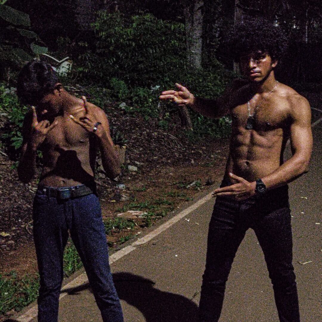 two bodybuilders standing on the side of a road posing for a picture